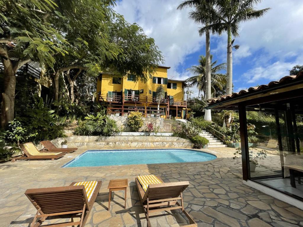 a swimming pool with two chairs and a house at Pousada Saint Germain in Búzios
