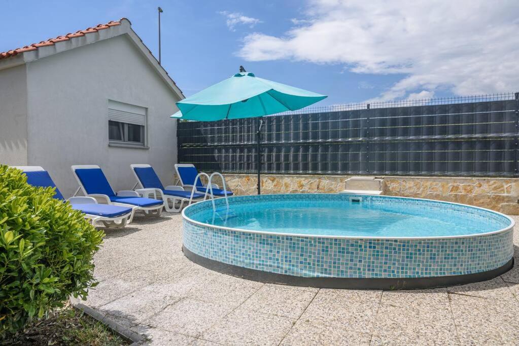 uma piscina com guarda-sol e cadeiras em New apartment with pool and jacuzzi only for you em Kaštela