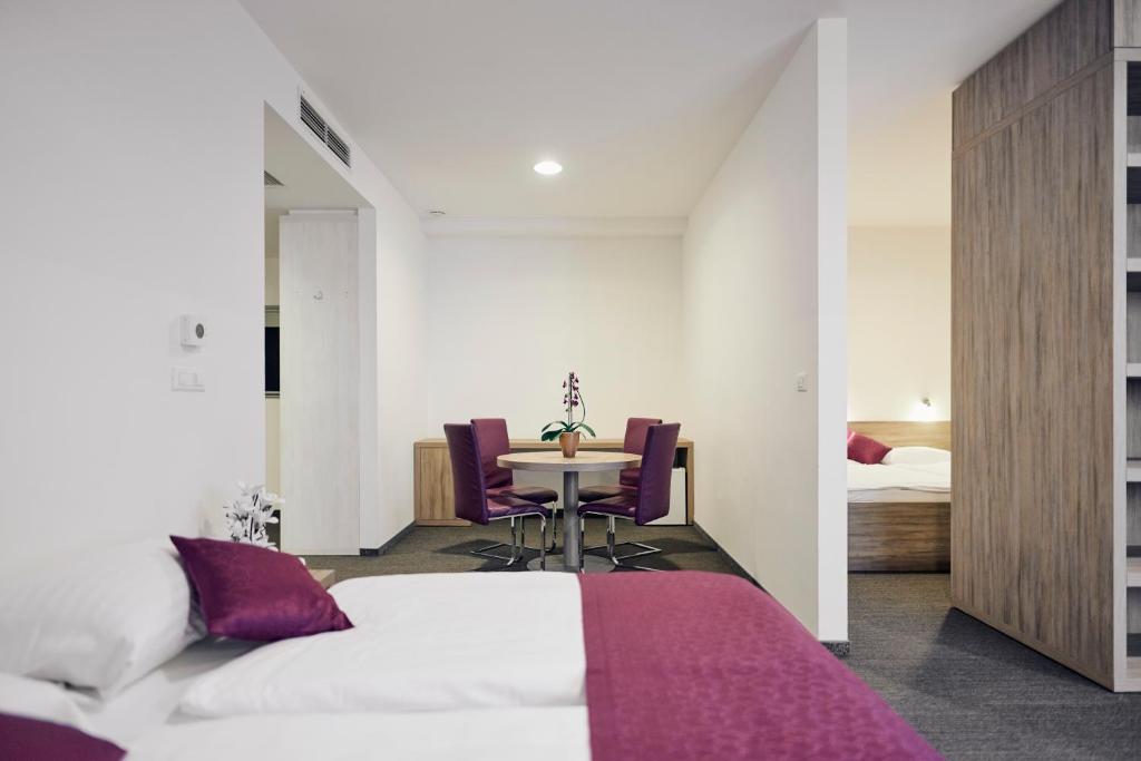 Schlafzimmer mit einem Bett und einem Tisch mit lila Stühlen in der Unterkunft Hotel Meksiko in Ljubljana