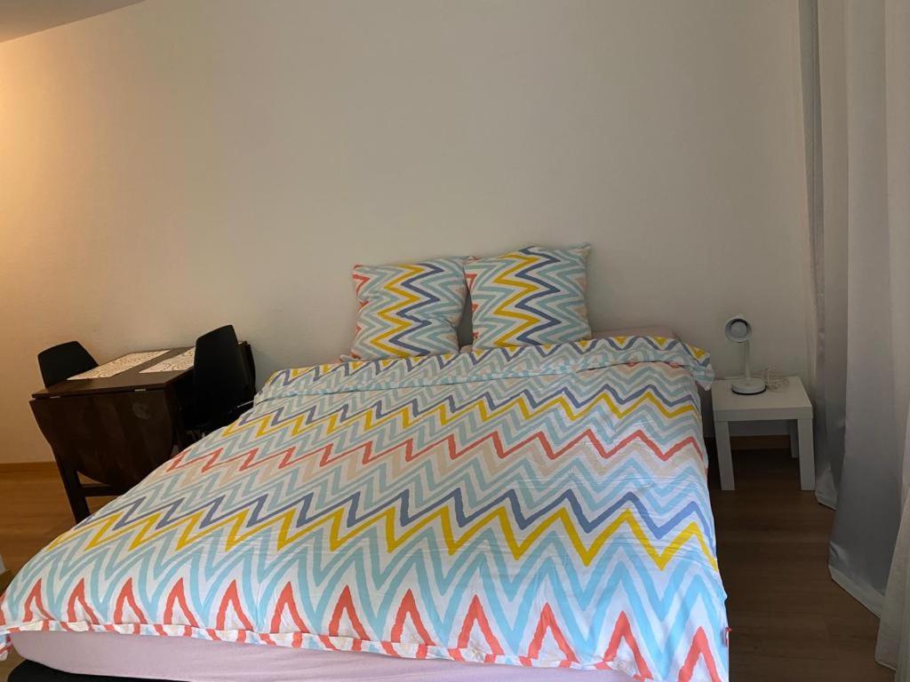 Apartment in Bern city centre في برن: غرفة نوم مع سرير مع لحاف ملون