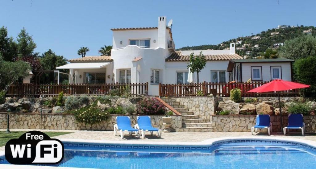 a villa with a swimming pool in front of a house at Villa Blanca in Calonge
