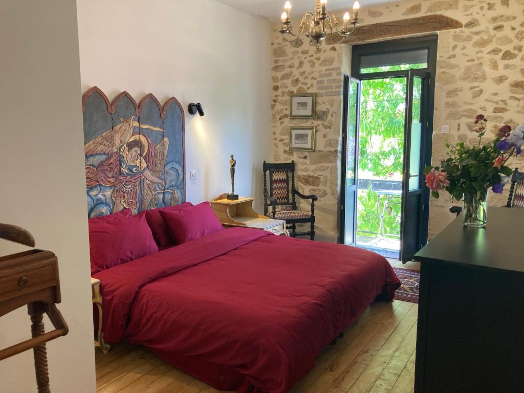a bedroom with a red bed with a painting on the wall at La Maison du Parc in Saint-Vite