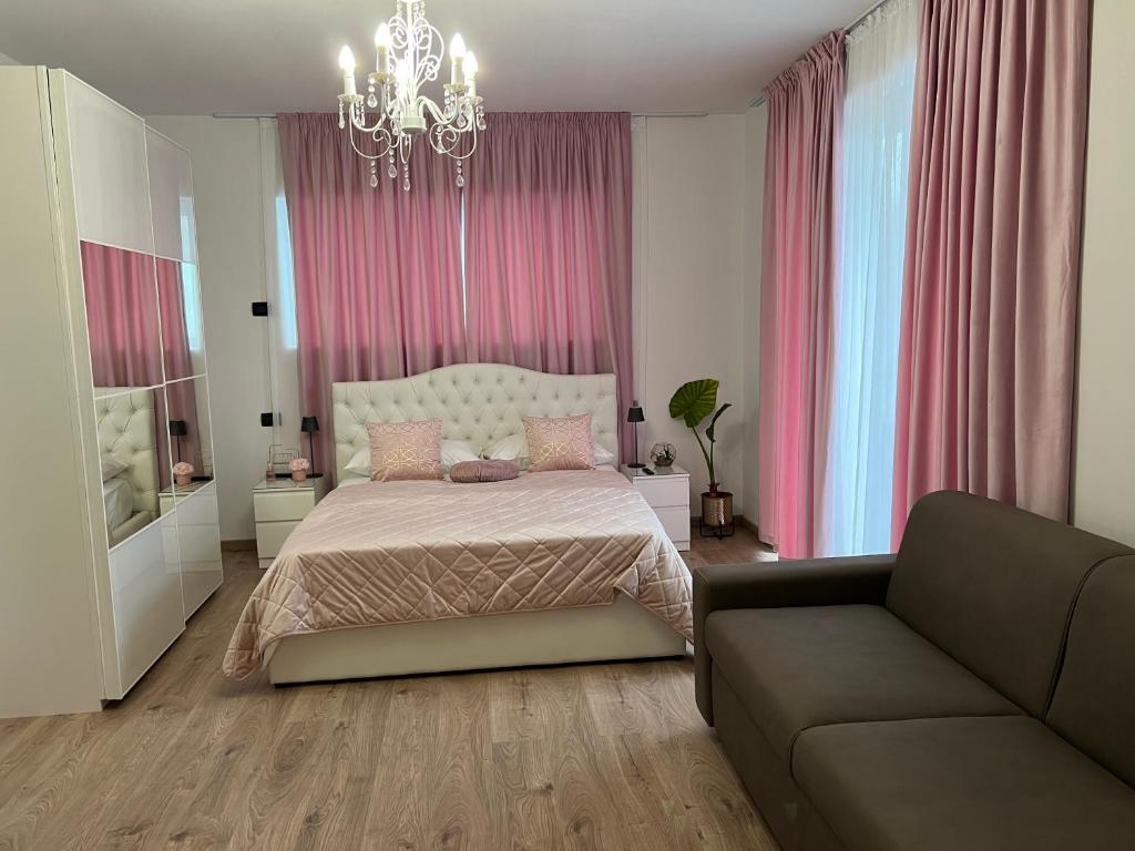 a bedroom with a bed and a couch and pink curtains at Casa Adriana in Rezzato