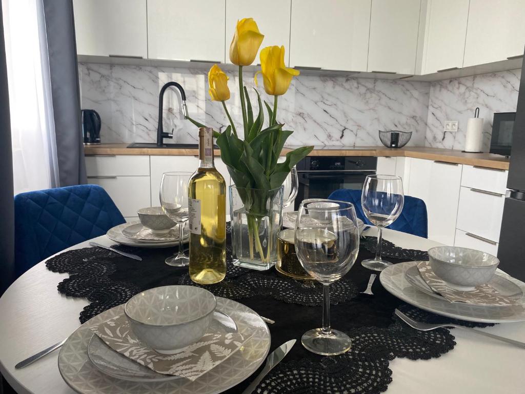 烏涅尤夫的住宿－UniLove Apartamenty，一张桌子,上面放着一瓶葡萄酒和黄色的鲜花