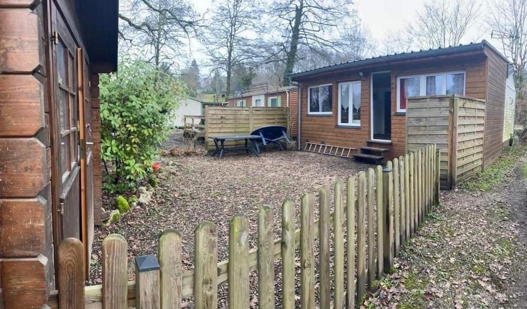 une clôture en bois devant une petite maison dans l'établissement Mobil Home 4 / 6 personnes, à Nances