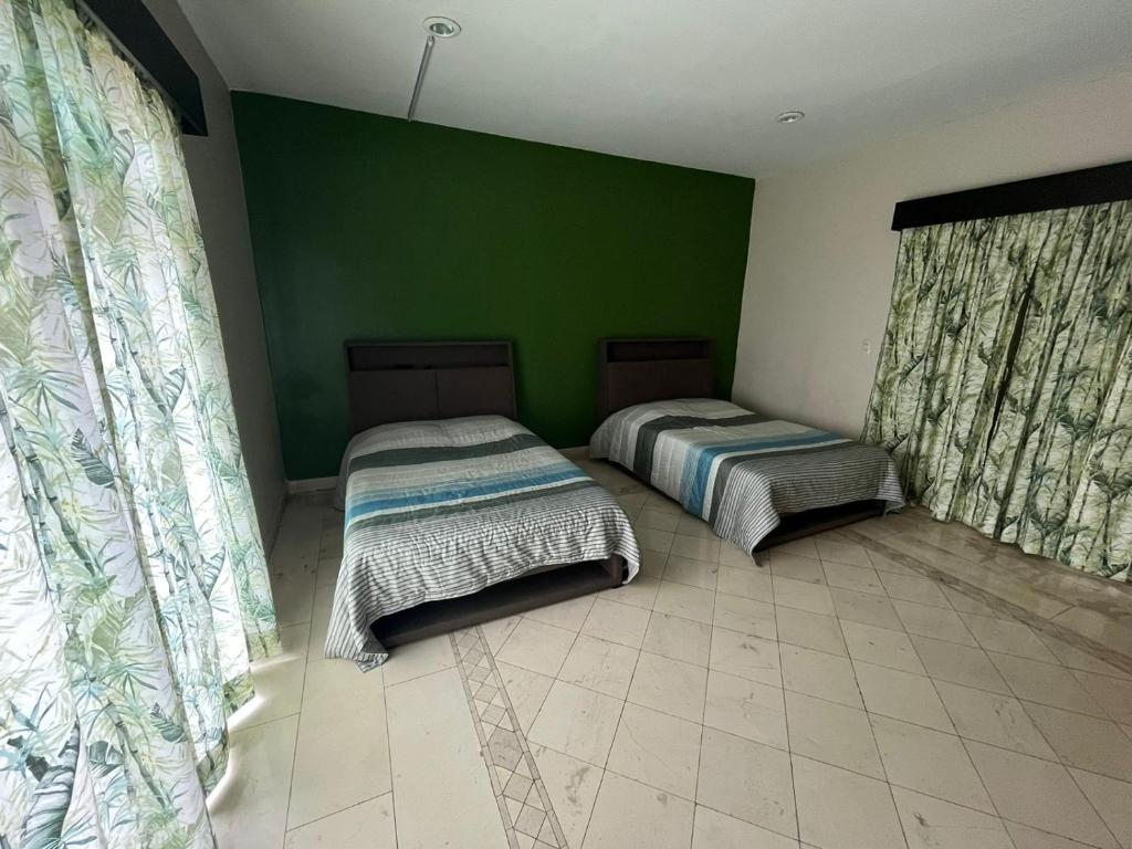 two beds in a room with a green wall at Agradable Habitación Ojo de agua in Orizaba