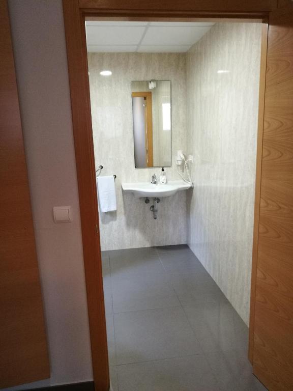 a bathroom with a sink and a mirror at Aparthotel El Faro in Cullera