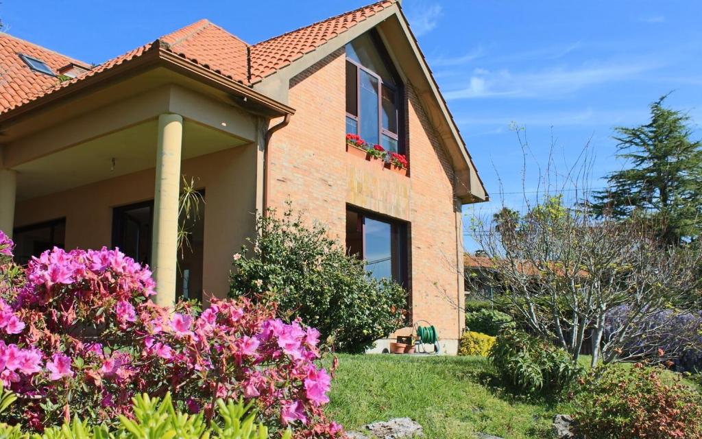 a house with pink flowers in the yard at Espectacular casa a dos minutos de Playa America in Nigrán