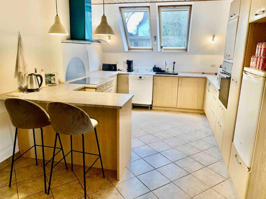 a kitchen with a counter and two bar stools at Big villa in stege near møns klint with trampolin in Stege