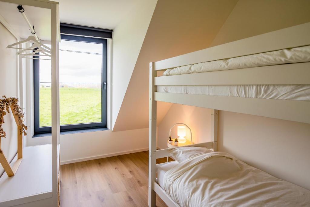a bedroom with two bunk beds and a window at Het Preshoekhuis in Lauwe