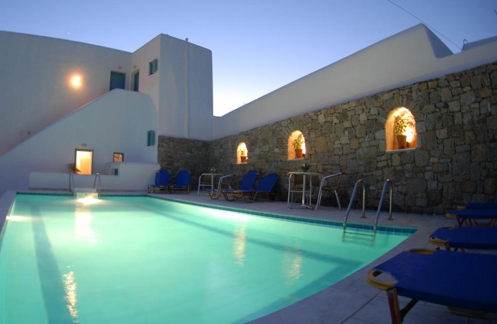 une piscine avec des chaises bleues et un mur en pierre dans l'établissement Yanna Luxury Suites (Asteri Suites), à Ornos