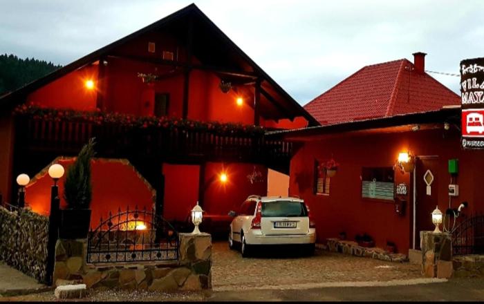 a car parked in front of a red building at Vila Maya in Băile Tuşnad