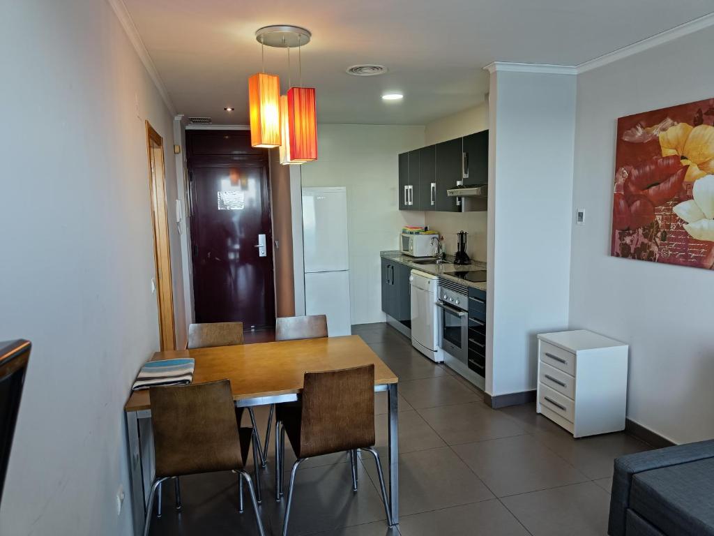 a kitchen and dining room with a table and chairs at Aparthotel El Faro in Cullera