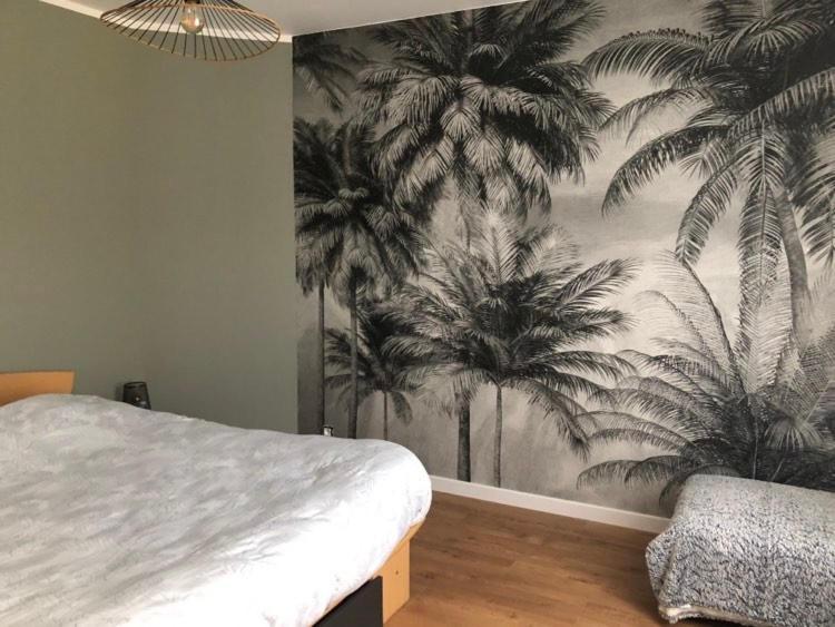 a bedroom with a mural of palm trees on the wall at chambre 24h du mans in Le Mans
