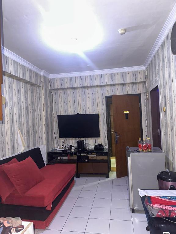 un soggiorno con divano rosso e TV a schermo piatto di Apartemen Casablanca 2Br a Giacarta