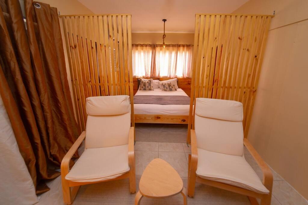 een kleine kamer met een bed en twee stoelen bij Danshari Aparta-Estudio Próximo al Malecón in Santa Cruz de Barahona