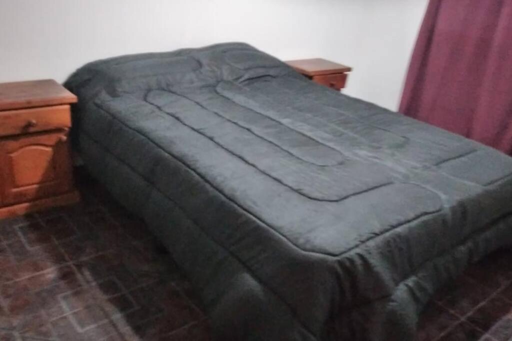 a bed with a green comforter in a bedroom at Casa amplia y cómoda in General Alvear