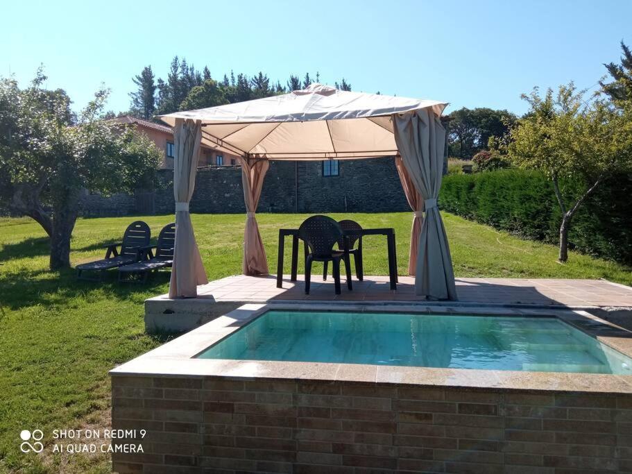 a table and chairs under an umbrella next to a pool at camino de santiago in Forcarei