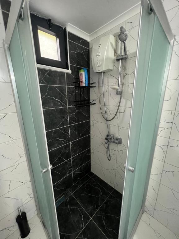 La salle de bains est pourvue d'une douche et de carrelage noir. dans l'établissement Ayliya köy evi, à Akcaabat