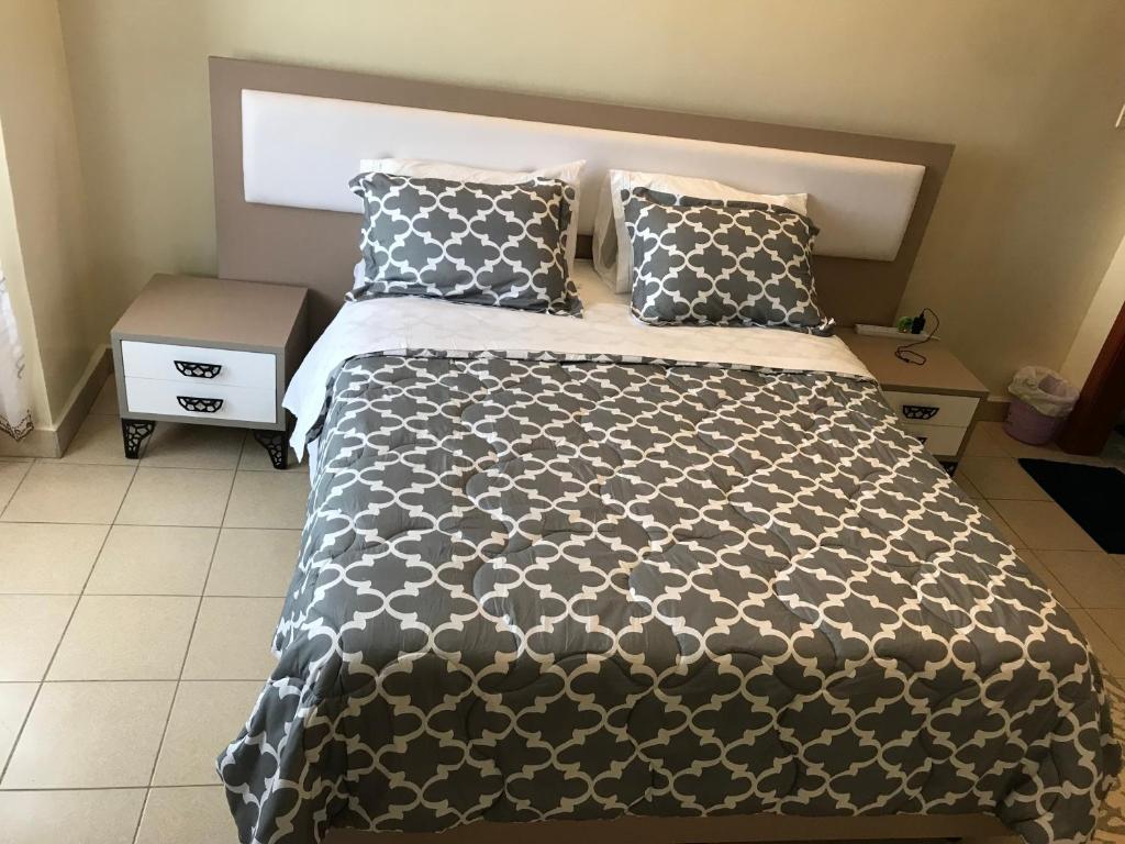 a bed with a black and white comforter and pillows at Maliaways Comfy Airbnb-Jkia in Nairobi