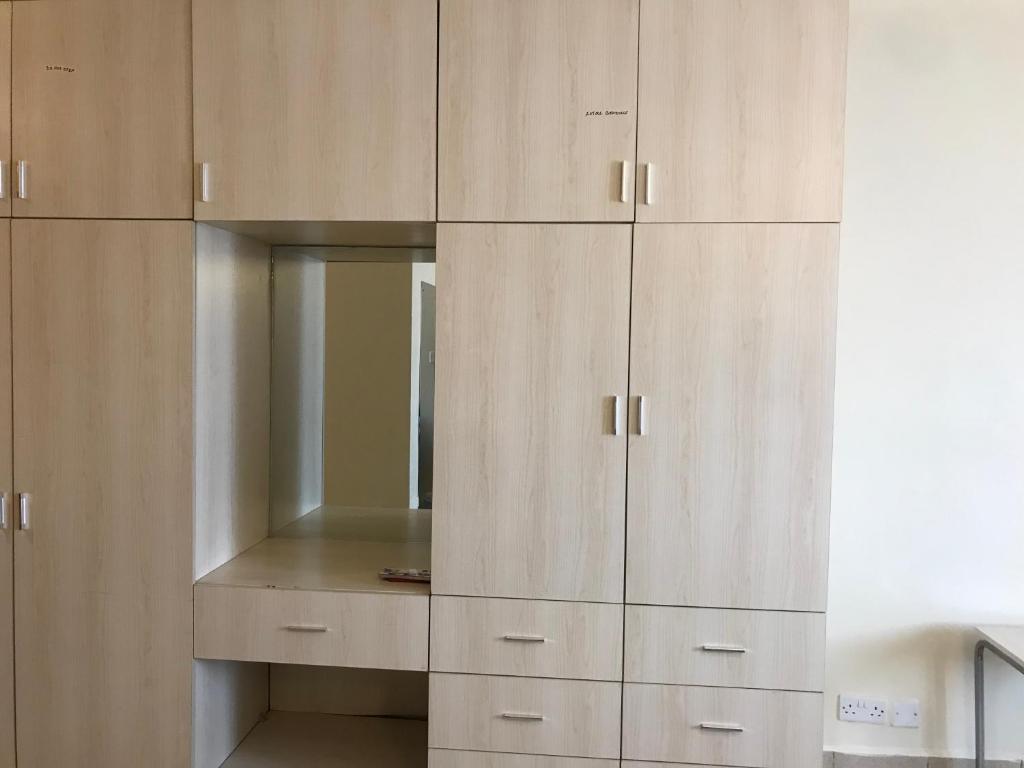 a large wooden cabinet with a mirror in it at Maliaways Comfy Airbnb-Jkia in Nairobi
