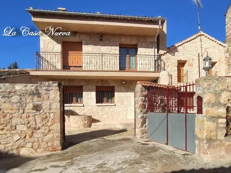 ein Steinhaus mit einem Tor und einem Balkon in der Unterkunft LA CASA NUEVA in Valleruela de Sepúlveda