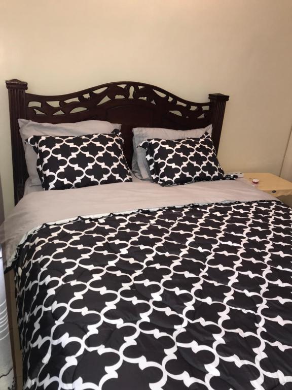 a bed with a black and white comforter and pillows at Maliaways Comfy Airbnb-Jkia in Nairobi