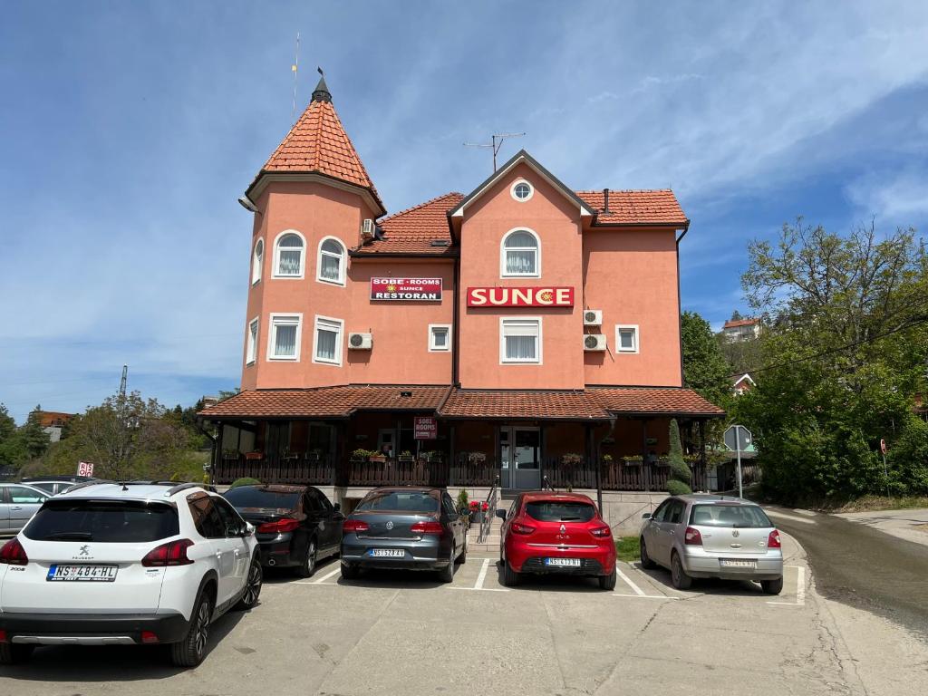 a large building with cars parked in a parking lot at Motel restoran Sunce in Sremska Kamenica