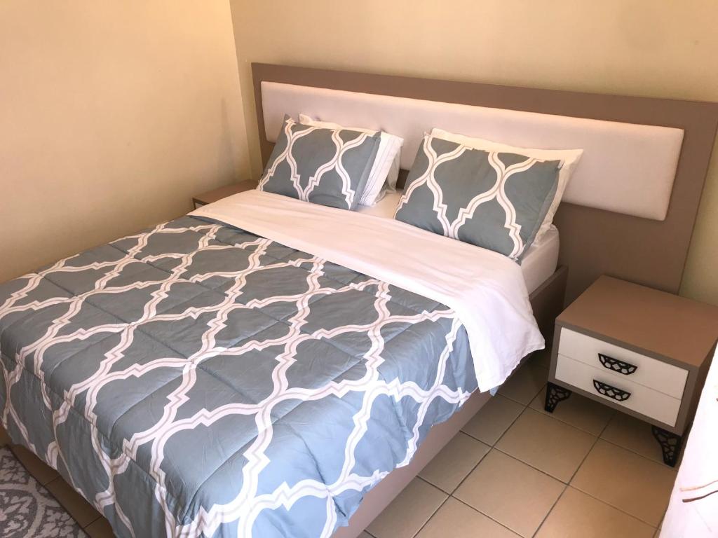 a bed with blue and white sheets and pillows at Maliaways Comfy Airbnb-Jkia in Nairobi