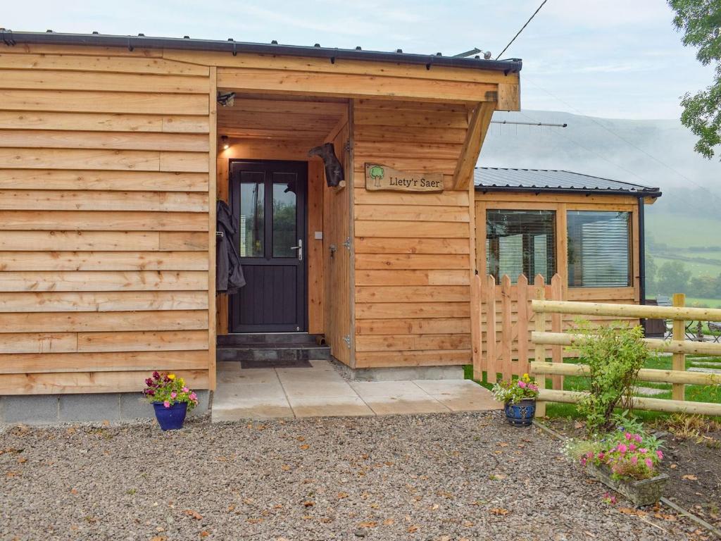 eine Holzhütte mit einer Tür und einem Zaun in der Unterkunft Lletyr Saer in Pen-y-bont-fawr