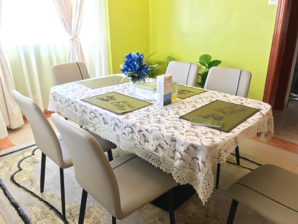 a dining room table with chairs and a white table cloth at Maliaways Comfy Airbnb-Jkia in Nairobi