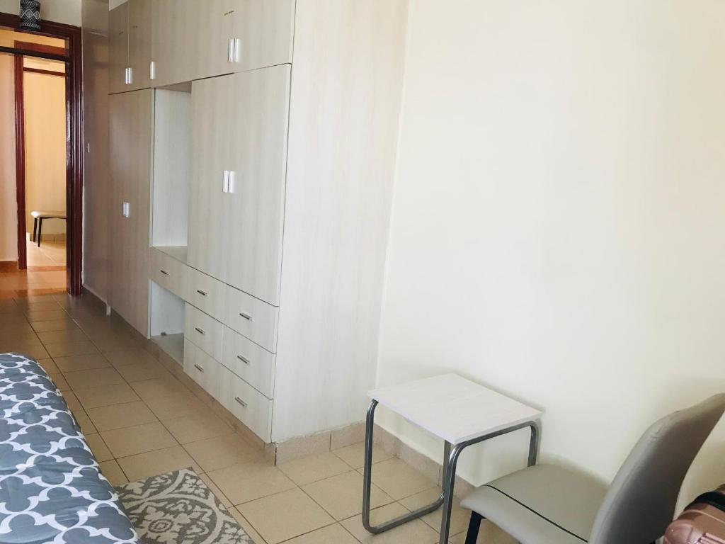 a bedroom with a dresser and a bed and a stool at Maliaways Comfy Airbnb-Jkia in Nairobi