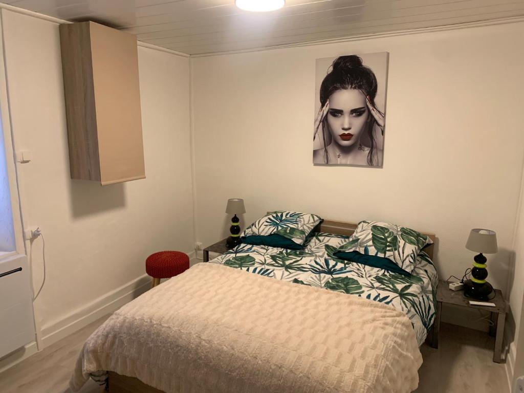 ein Schlafzimmer mit einem Bett und einem Bild einer Frau in der Unterkunft Appartement cœur de maurienne 2 in Saint-Étienne-de-Cuines