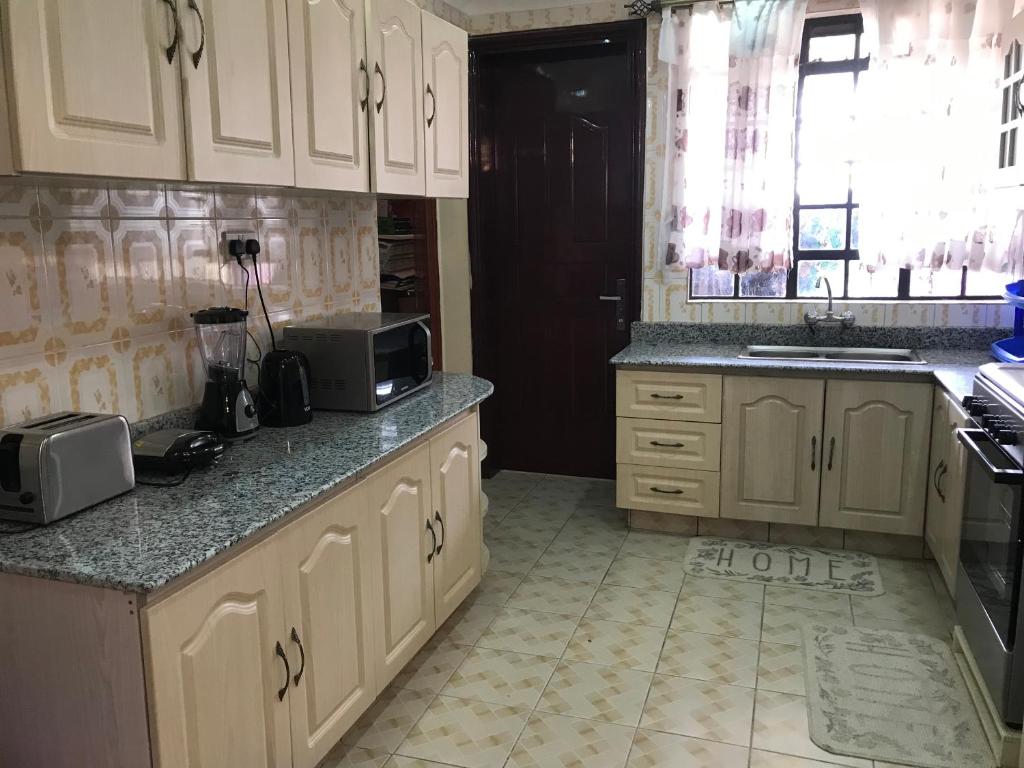 a kitchen with white cabinets and a counter top at Maliaways Comfy Airbnb-Jkia in Nairobi
