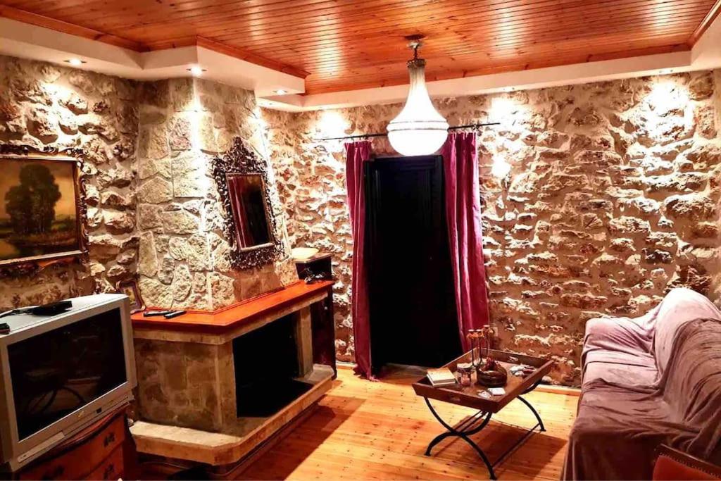 sala de estar con pared de piedra y TV en Πέτρινο πολυτελές εξοχικό, en Daras