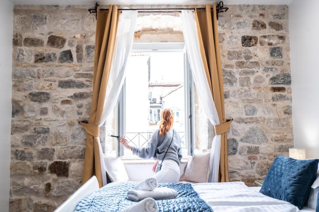 a woman looking out the window of her bedroom at Luxury Rooms Lucija and Luka in Split