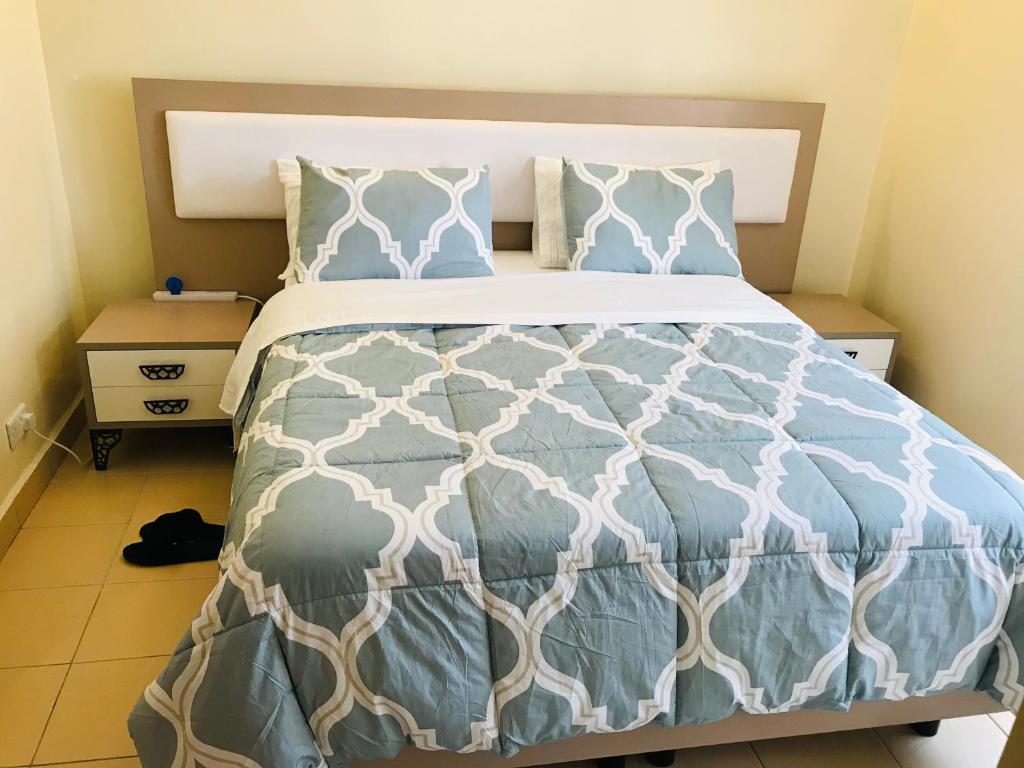 a bedroom with a bed with a blue and white comforter at Maliaways Comfy Airbnb-Jkia in Nairobi