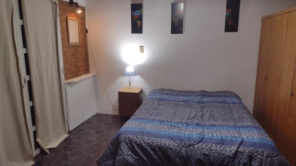 Dormitorio pequeño con cama y lámpara en Monoambiente interno en Trelew en Trelew