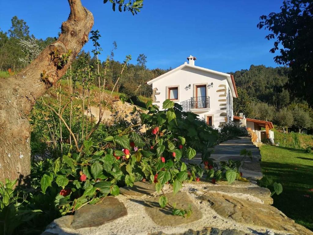 une maison blanche avec des fleurs devant elle dans l'établissement A Casa dos Avós - Alojamento Local, à Sertã