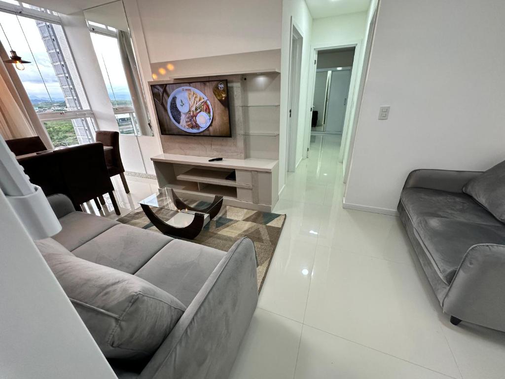 a living room with a couch and a tv at Apartamento á 300 metros da praia de Itaparica e efrente o shoping bullevard in Vila Velha