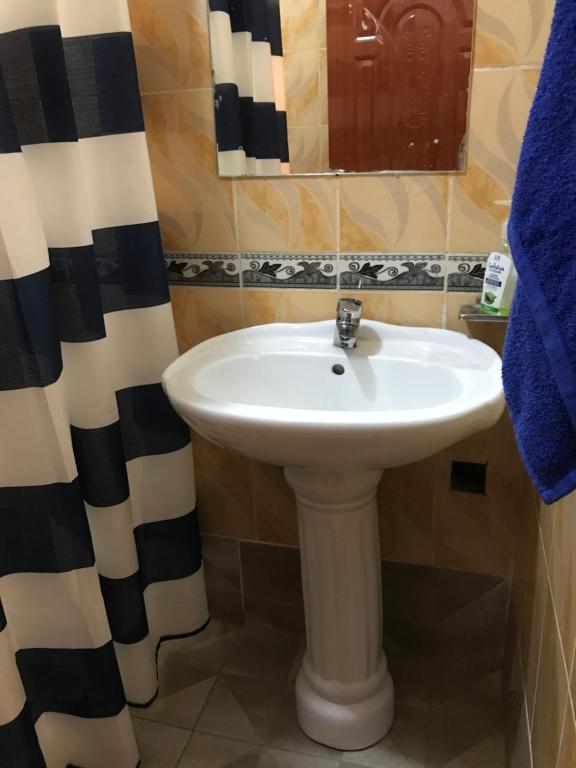 a bathroom with a white sink and a mirror at Maliaways Comfy Airbnb-Jkia in Nairobi