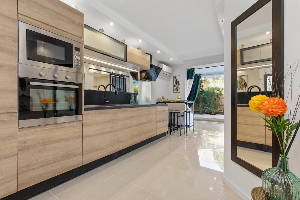 une cuisine avec des armoires en bois et un vase avec des fleurs orange dans l'établissement Cookie Love - entièrement neuf - à 100 m de l'entrée du village naturiste, au Cap d'Agde