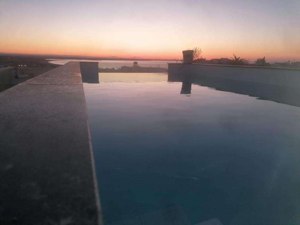 a swimming pool with a sunset in the background at Nature Guesthouse in Lagos