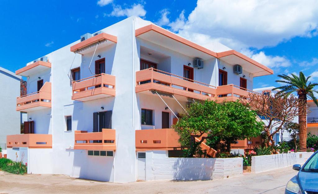 biały budynek z pomarańczowymi balkonami i palmą w obiekcie Anchris Paleochora w mieście Palaiochóra