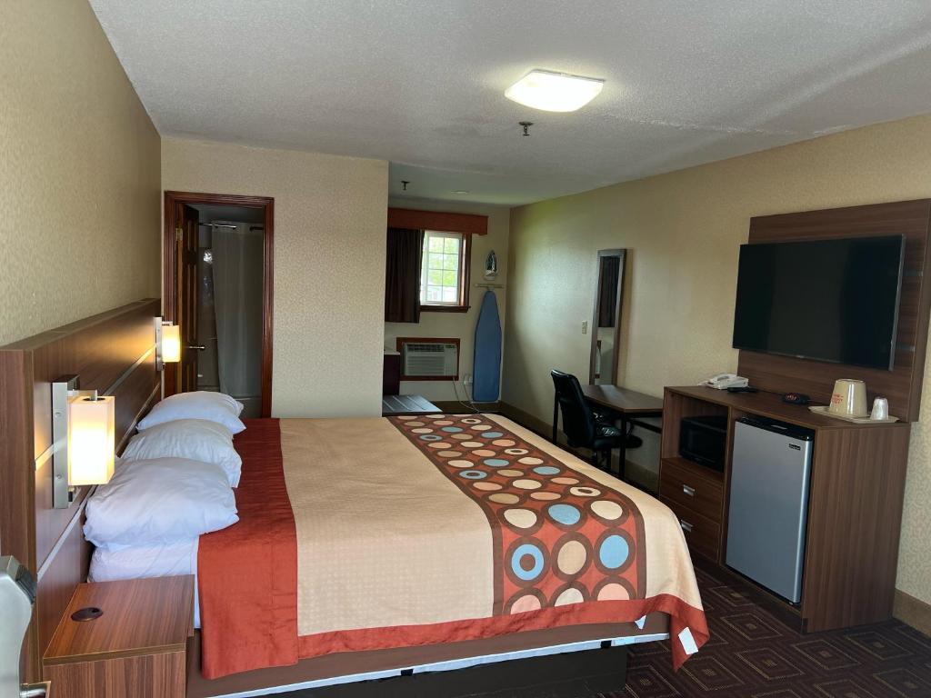 um quarto de hotel com uma cama e uma televisão de ecrã plano em American Inn em Branford