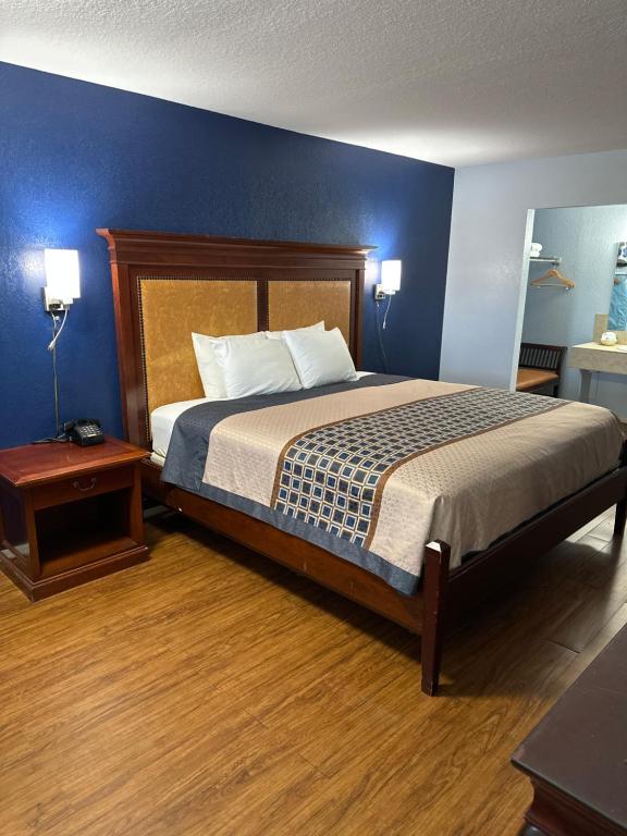 1 dormitorio con 1 cama grande y pared azul en Tanglewood Motel, en Frederick