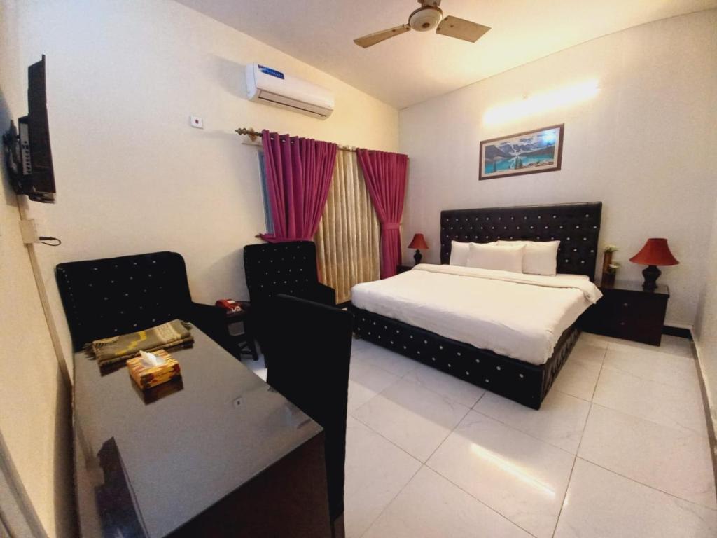 a bedroom with a bed and a table and a desk at Travel Inn islamabad in Islamabad