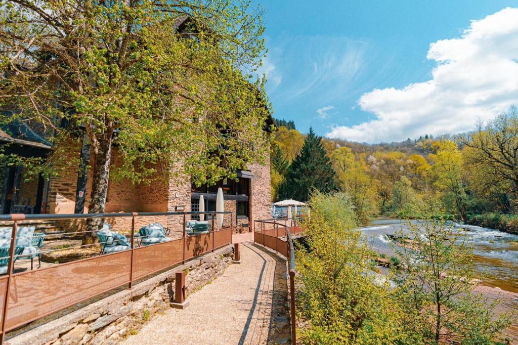 een gebouw met een loopbrug naast een rivier bij Moulin de Cambelong- Emilie & Thomas in Conques-en-Rouergue