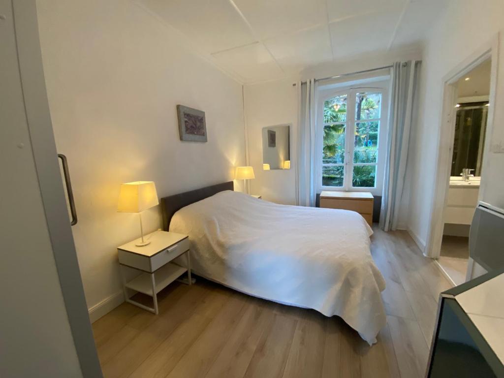 a white bedroom with a bed and a window at St Guenole&#39; Studio Apartment in Landévennec