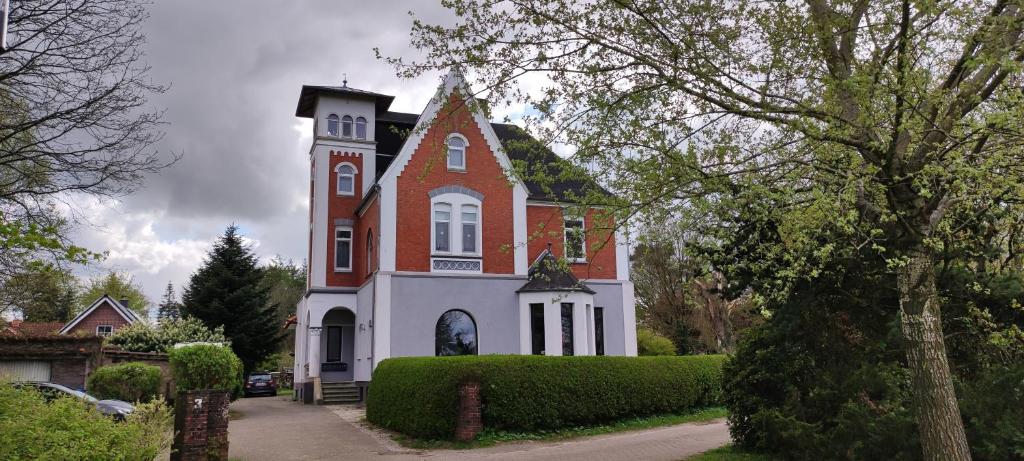 a large brick and white building with a clock tower at Villa Kunterbunt, Gemütlichkeit am Waldesrand in Drangstedt